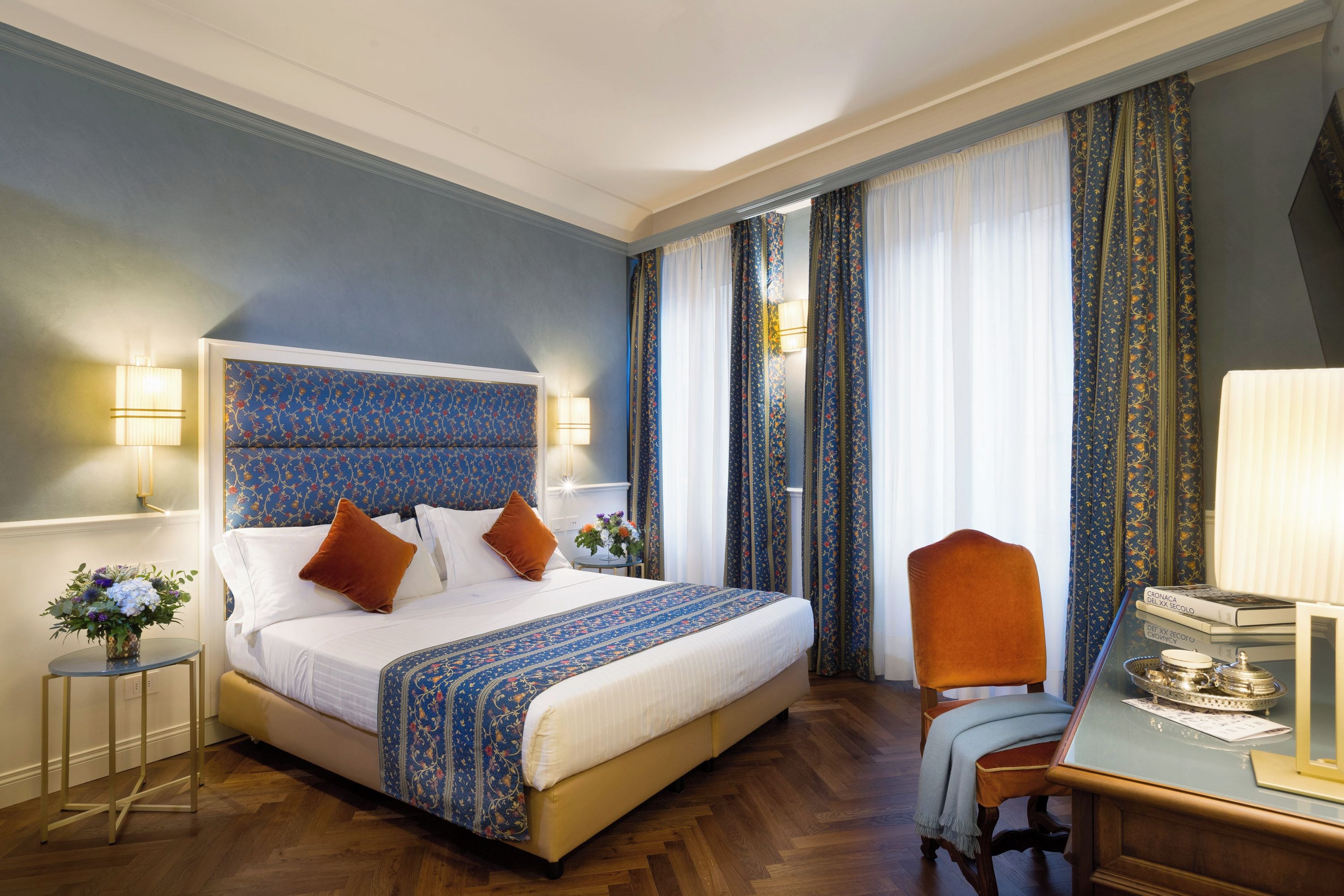 Une chambre d’hôtel avec un grand lit, une chaise, un bureau et une fenêtre avec des rideaux.
