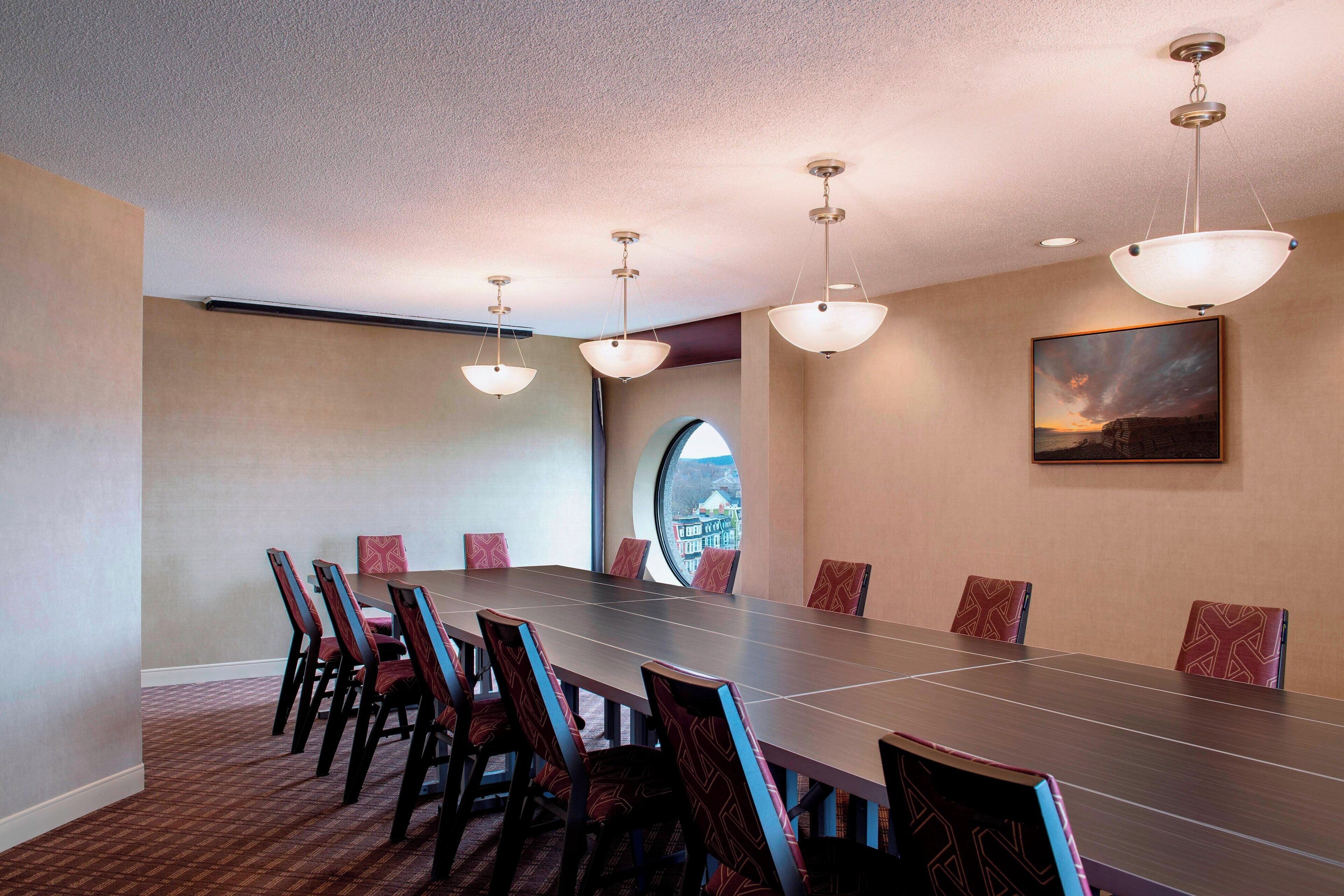 A conference room with a long table, chairs, and pendant lighting.