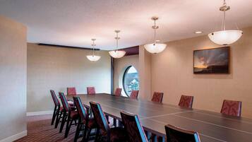 A conference room with a long table, chairs, and pendant lighting.