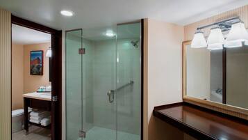 Un baño moderno con ducha envuelta en vidrio, tocador con espejo y encimera de madera.