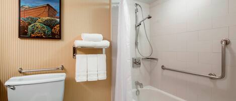 Une salle de bain équipée de toilettes, d’une douche avec des barres d’appui et d’un porte-serviettes.