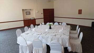 Un salón de conferencias con una gran mesa ovalada, sillas blancas y un centro de mesa floral.