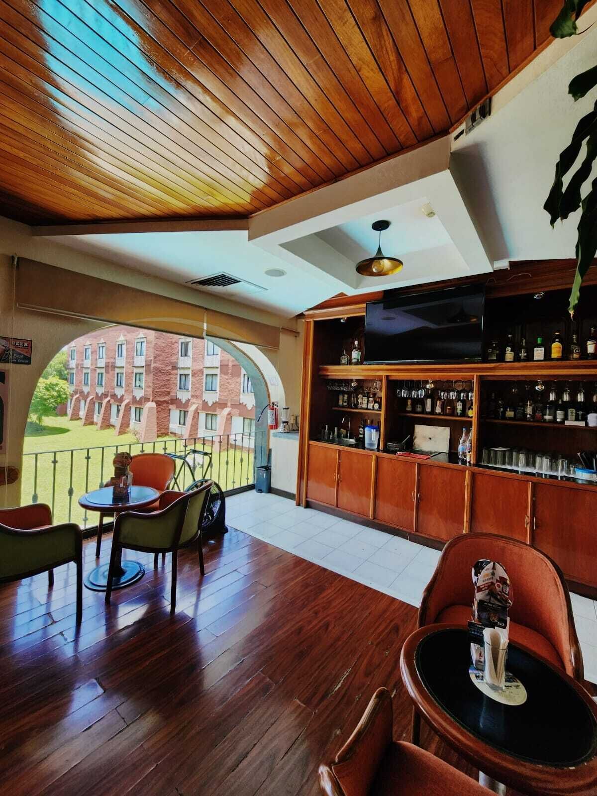 A bar area with wooden flooring, a television, and shelves with bottles.