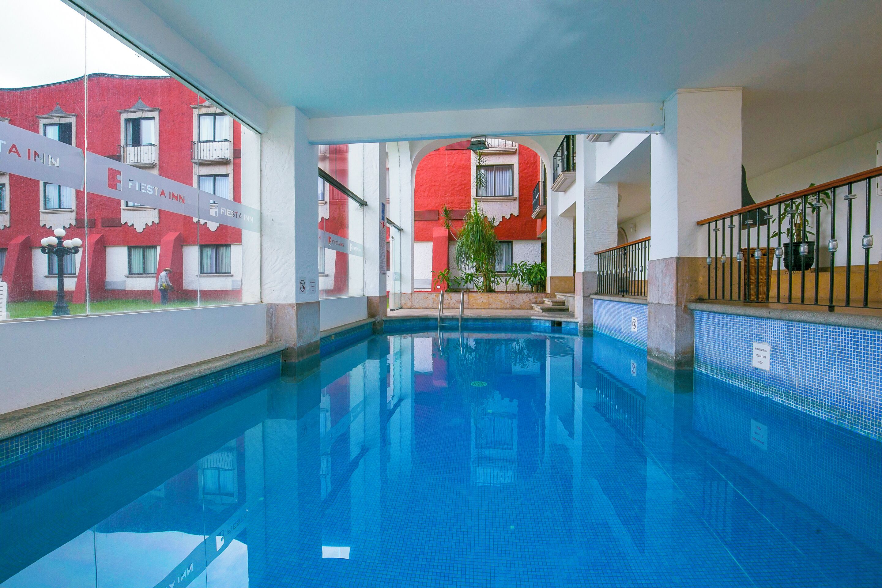 Una piscina interna con acqua cristallina, circondata da un edificio con balconi e una facciata rossa.
