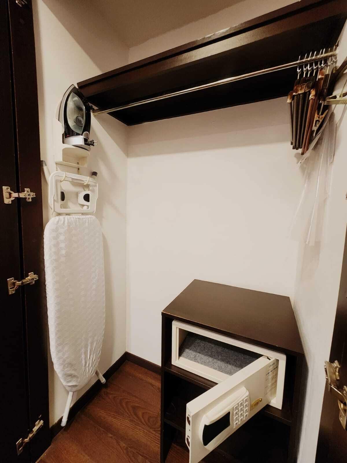 A compact room with a microwave, a small cabinet, and a hanging rack with utensils.