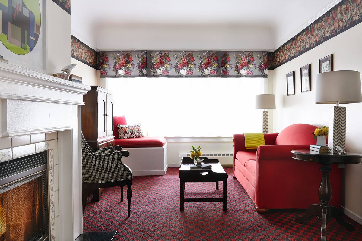A living room with a fireplace, red sofa, and a patterned carpet.