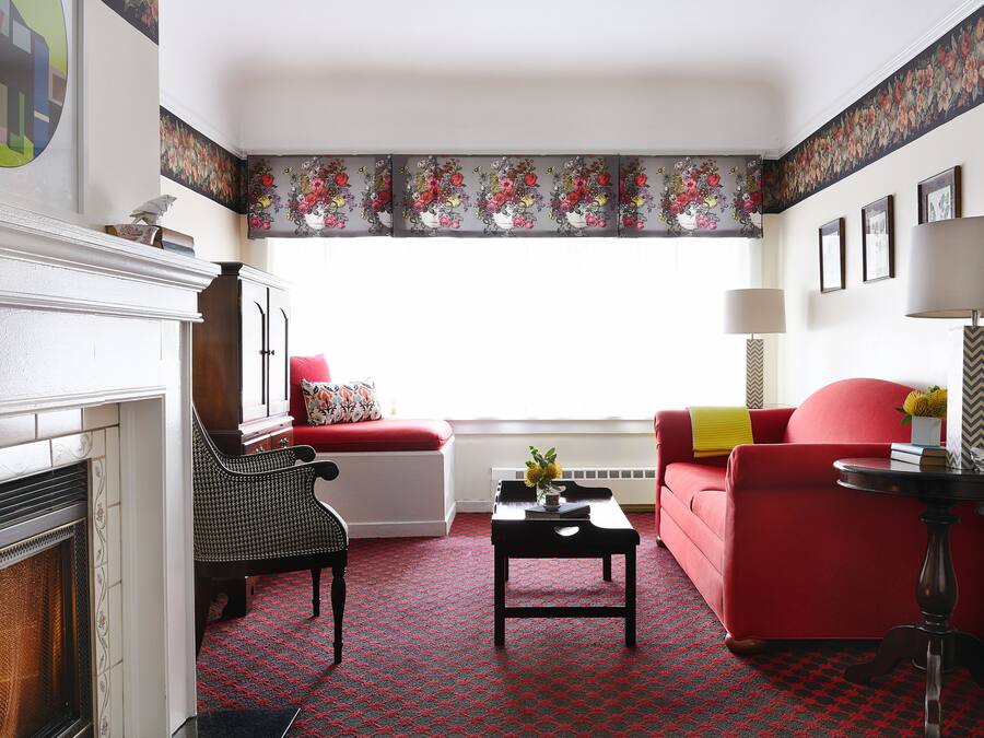 A living room with a fireplace, red sofa, and a patterned carpet.