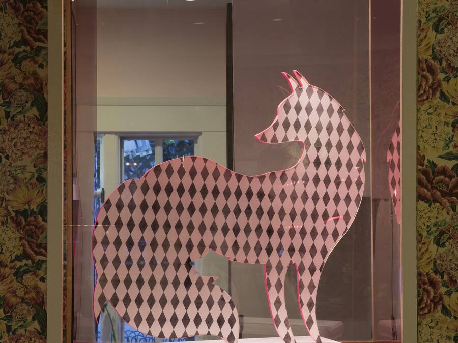 A framed artwork of a stylized animal with a checkered pattern, displayed against a floral wallpaper background.