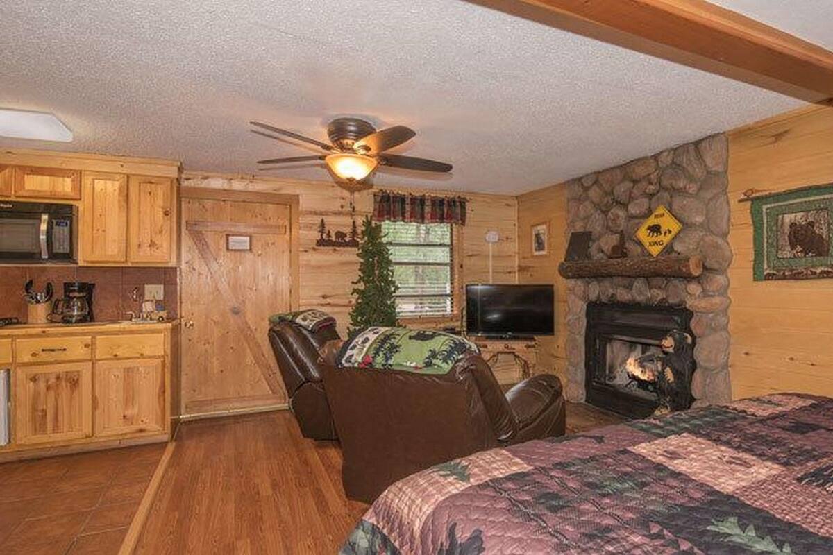 A cozy cabin interior with a dining area, a fireplace, a television, and a comfortable seating area.