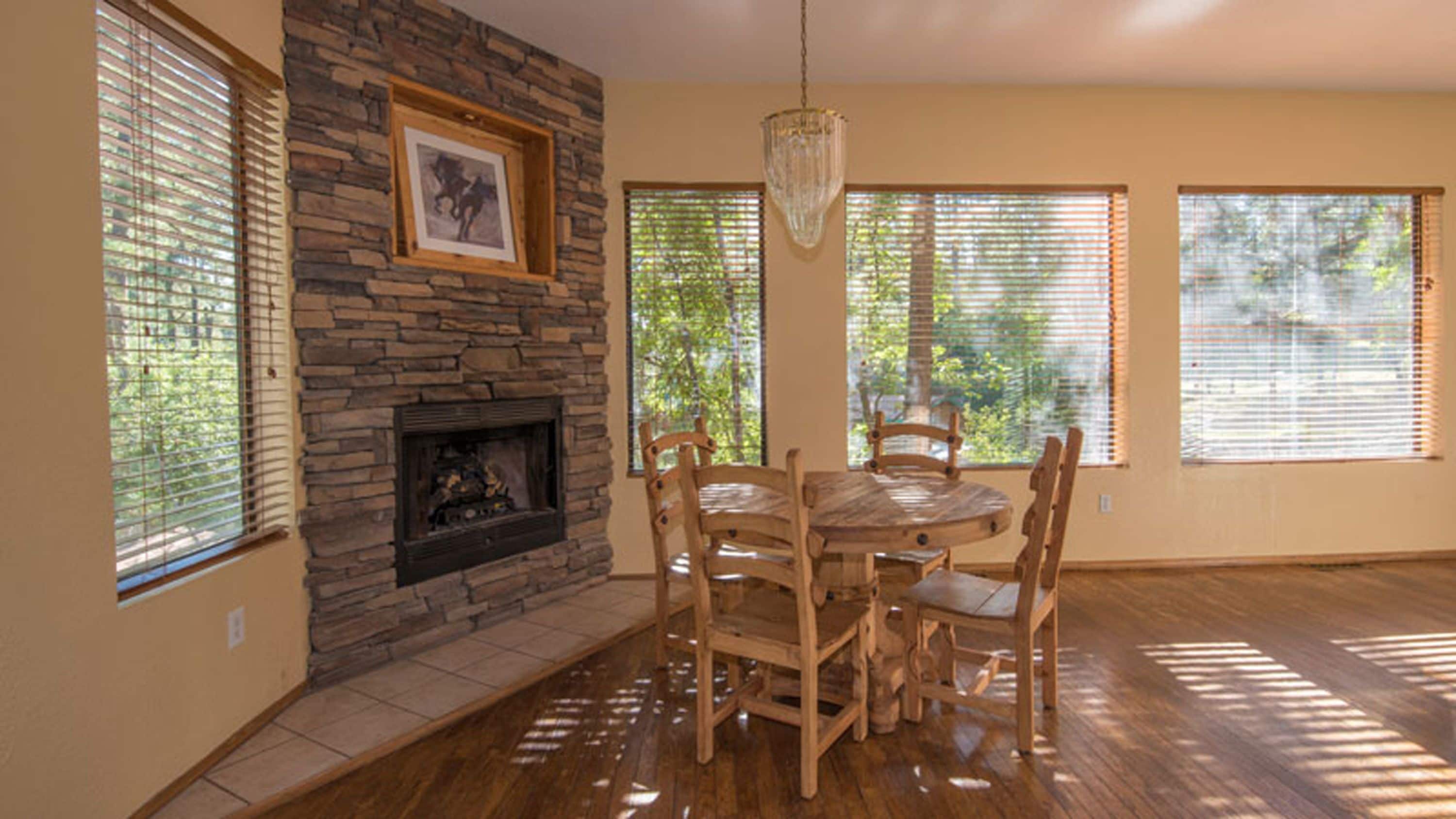 Comedor con chimenea de piedra, mesa y sillas de madera.