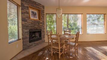 Comedor con chimenea de piedra, mesa y sillas de madera.
