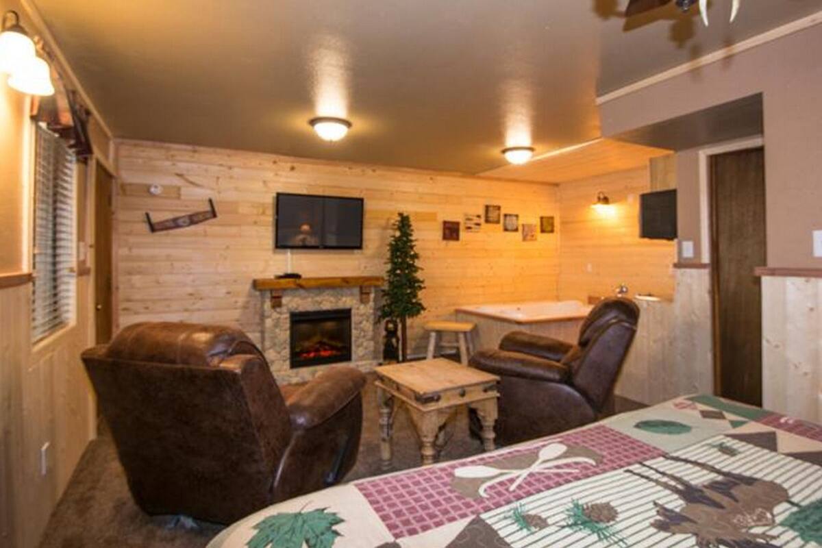 A cozy room with a fireplace, leather chairs, a small table, and a quilted tablecloth.