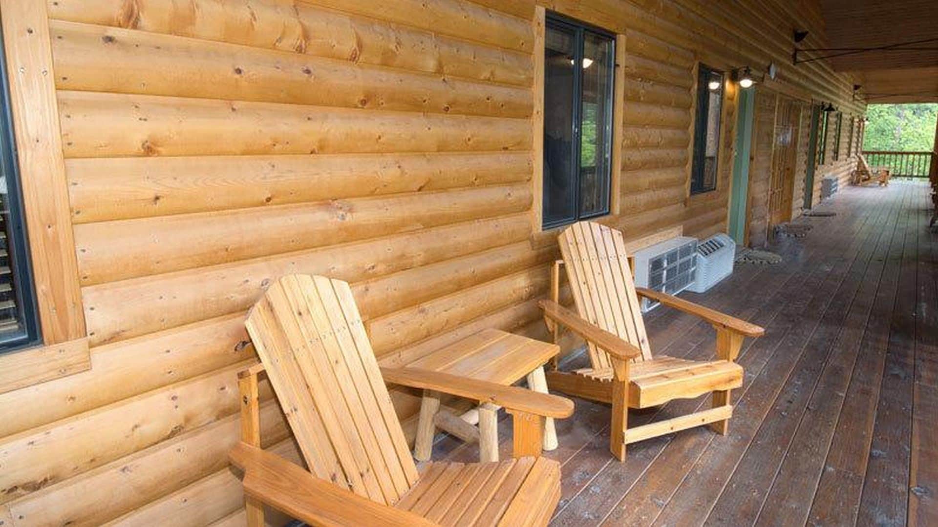 A wooden cabin with two Adirondack chairs on a porch.