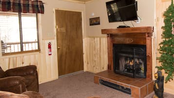 Una sala de estar con chimenea, sofás de cuero, un televisor montado y un árbol de Navidad.