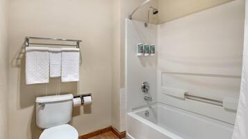 A bathroom with a toilet, two towels on a rack, a shower with a glass door, and a toilet paper holder.