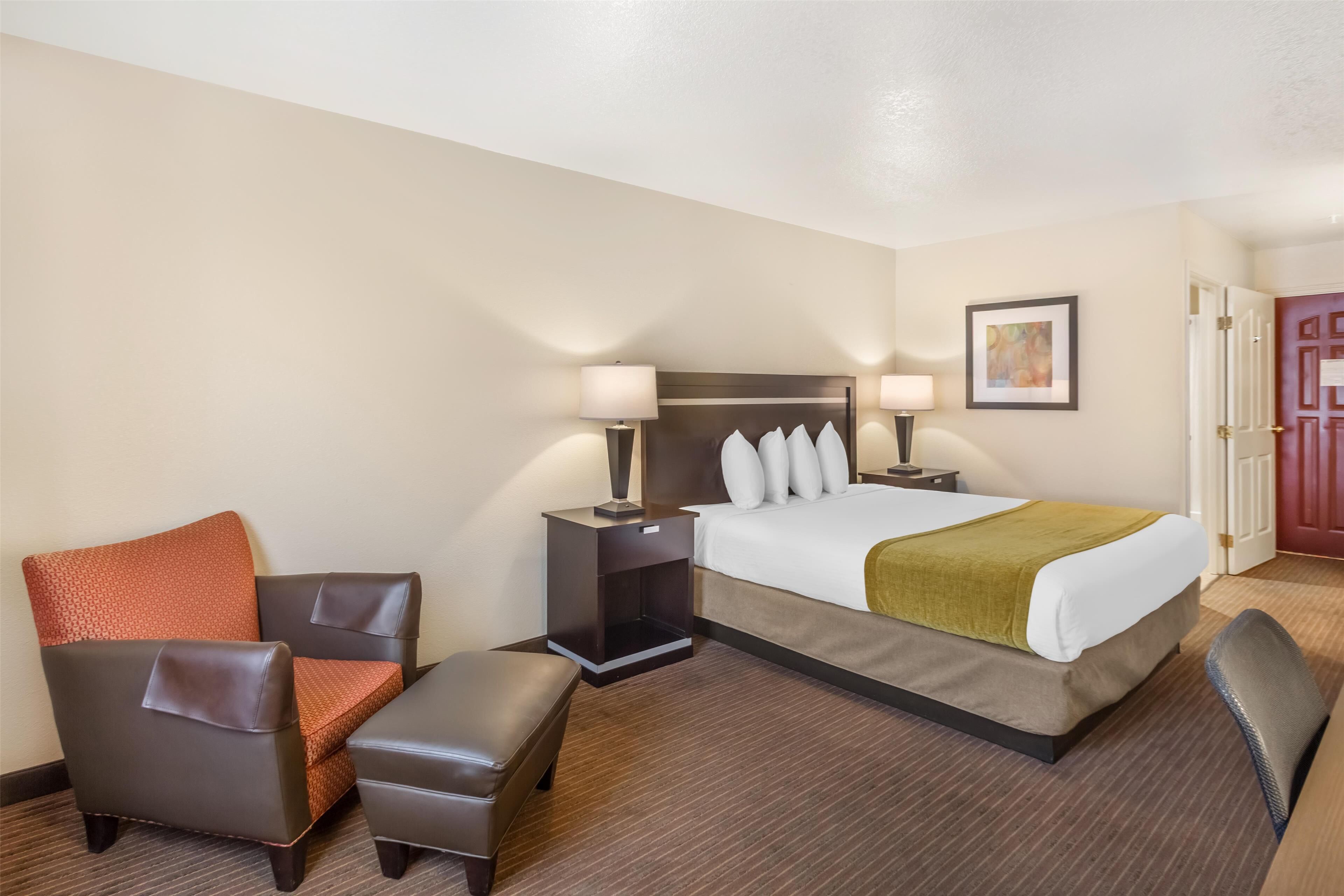 A hotel room with a bed, a chair, a desk, and a nightstand.