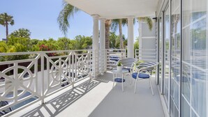 A balcony with white railings, a table, and two chairs.