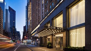 A row NYC building with a marquee sign, large windows, and a street view.