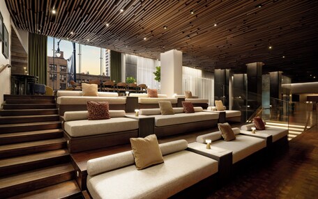 A modern interior with tiered seating, a staircase, and a view of the city.