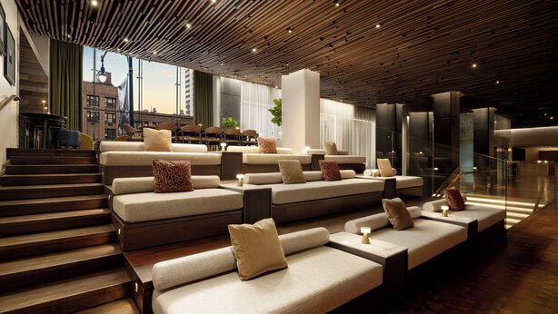 A modern interior with tiered seating, a staircase, and a view of the city. - ROW NYC (New York)