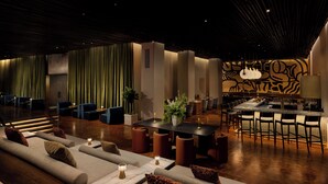 A modern lounge area with sofas, a dining table, and a bar with chairs.