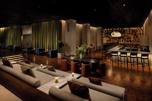 A modern lounge area with sofas, a dining table, and a bar with chairs. - ROW NYC (New York)