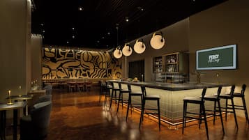 A bar area with a counter, stools, and a patterned wall in the background.