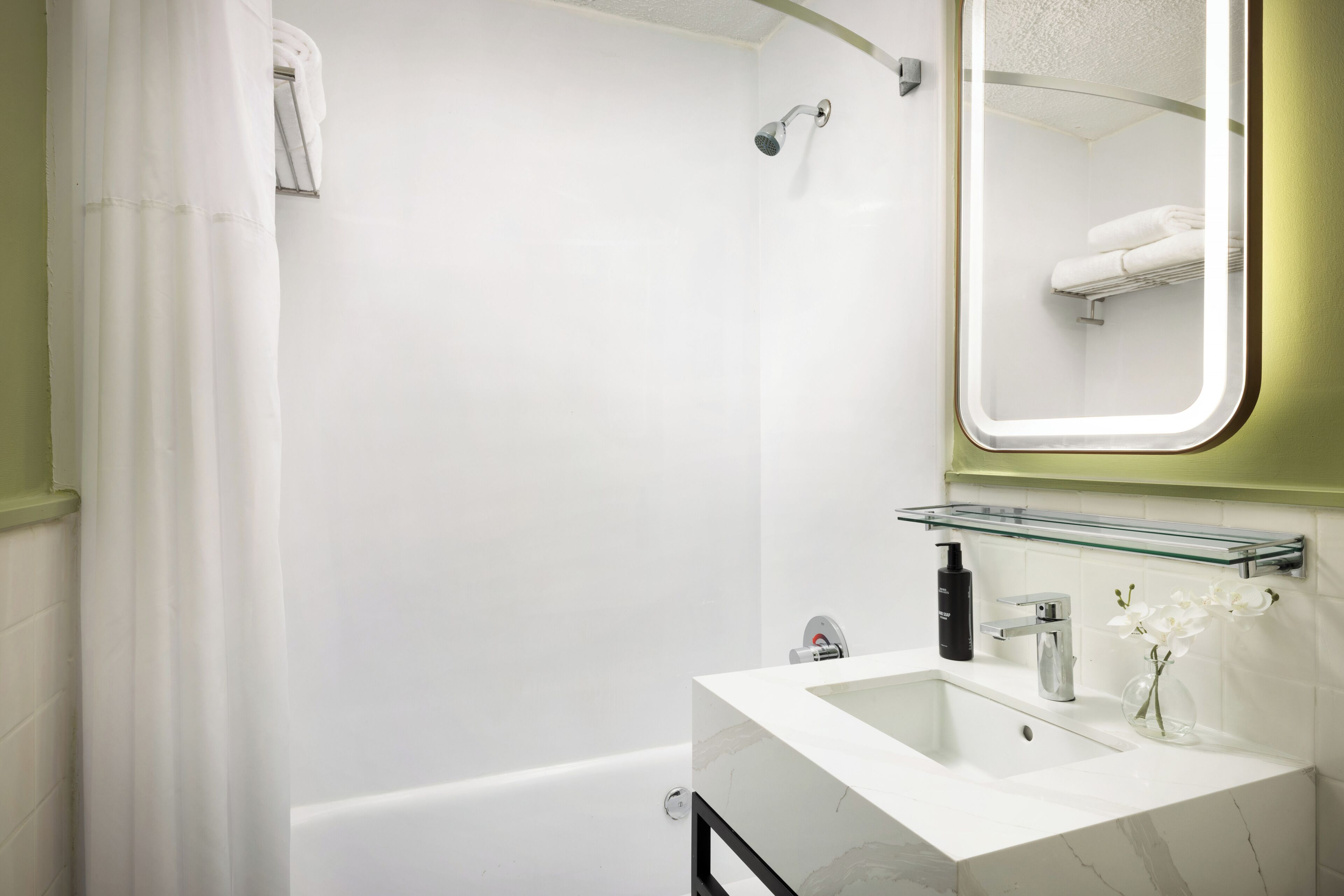 A modern bathroom with a shower, a sink with a glass shelf, and a mirror.