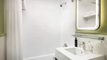 Un baño moderno con ducha, lavabo y estante de vidrio, además de un espejo.
