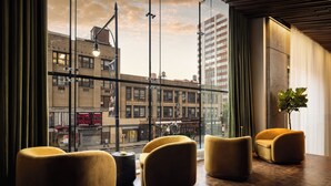 A modern interior with large windows, a plant, and a view of the cityscape. - ROW NYC (New York)