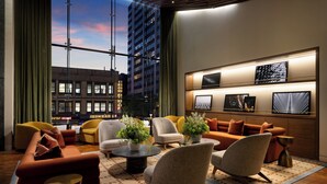 A modern lounge with a city view, comfortable seating, and decorative plants. - ROW NYC (New York)