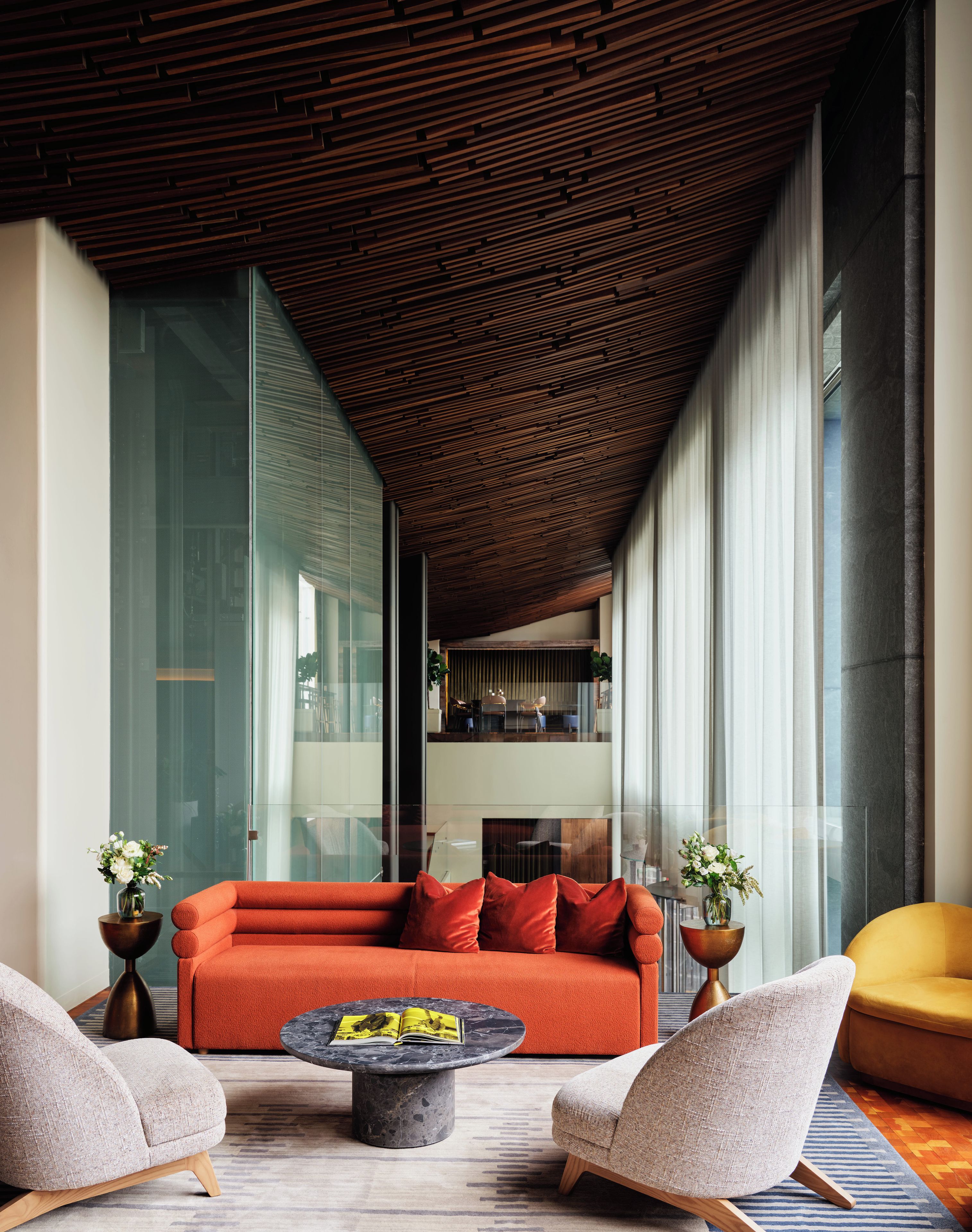 A modern living room with a wooden ceiling, a red sofa, and a round coffee table.