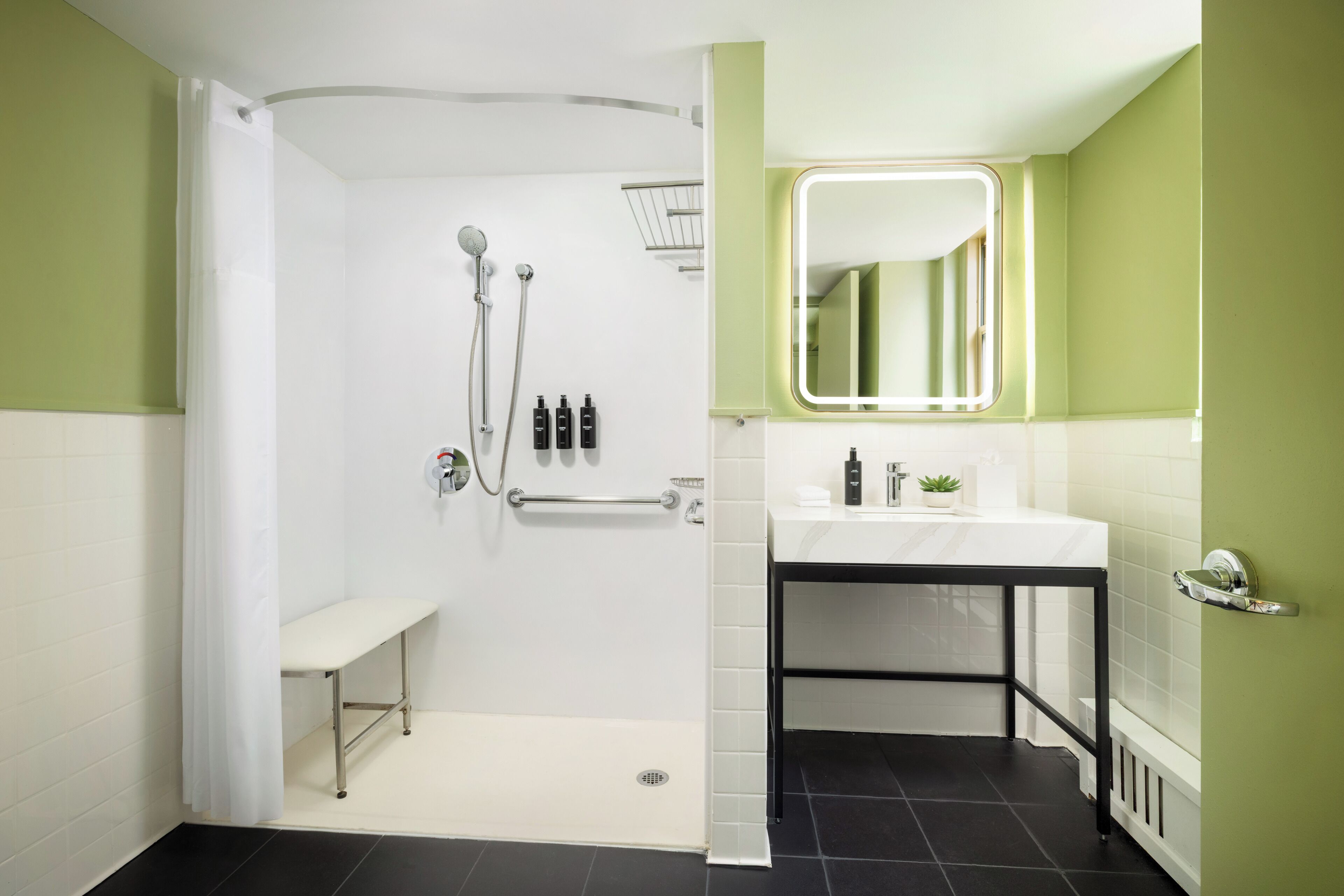 A modern bathroom with a shower, bench, sink, and mirror.
