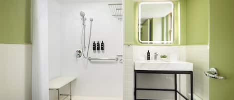 A modern bathroom with a shower, bench, sink, and mirror.