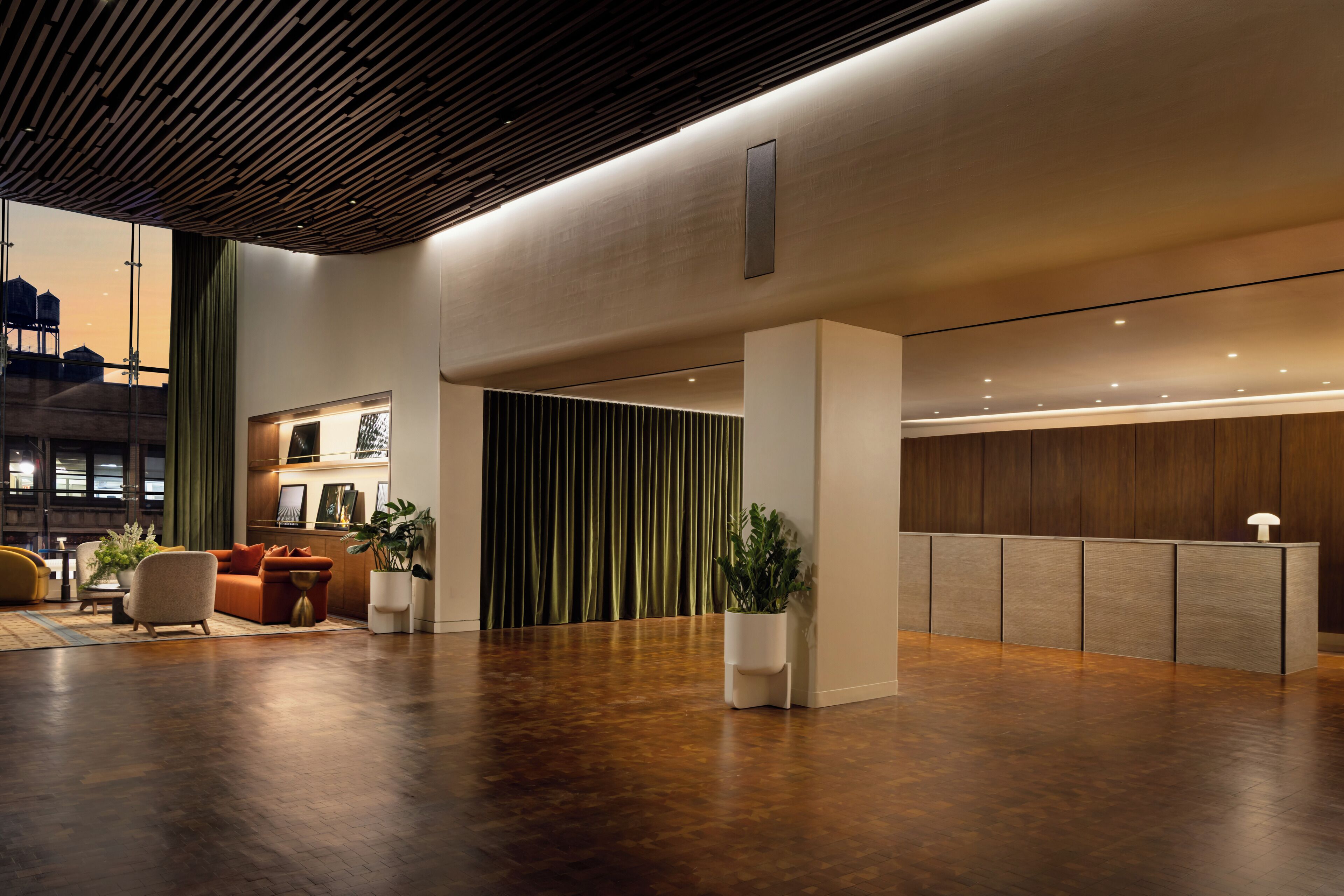 Een ruime lobby met een houten plafond, een receptiebalie en zithoeken.