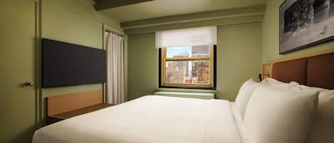 Habitación de hotel con cama, televisión montada en la pared, ventana con vista a la ciudad y lámpara de techo.