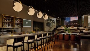 A bar area with a long counter, multiple stools, and a variety of bottles and glasses on shelves. - ROW NYC (New York)