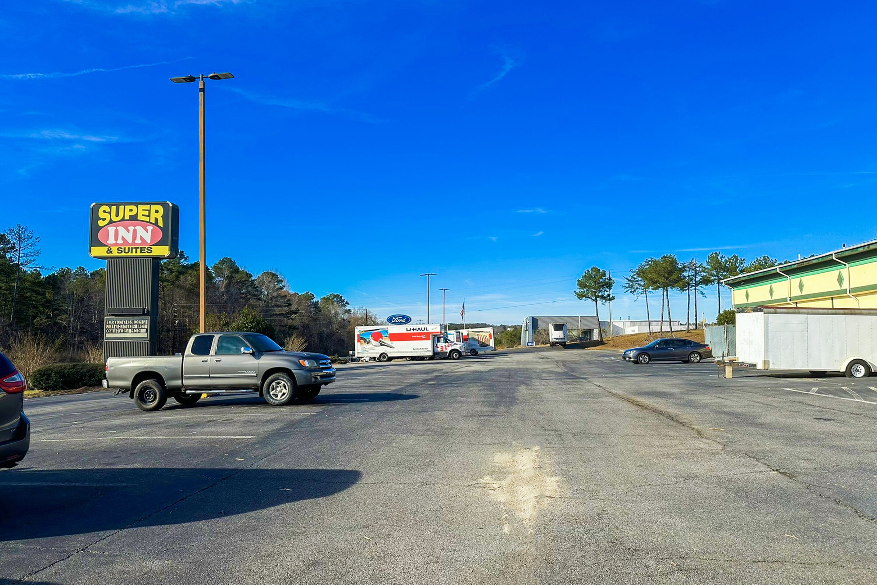 A parking lot with a Super Inn sign, a U-Haul truck, and a few cars.