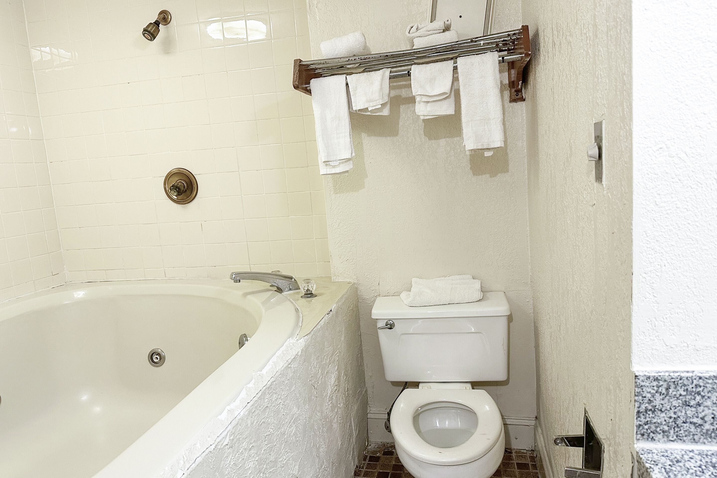 A bathroom with a bathtub, toilet, and towel rack.