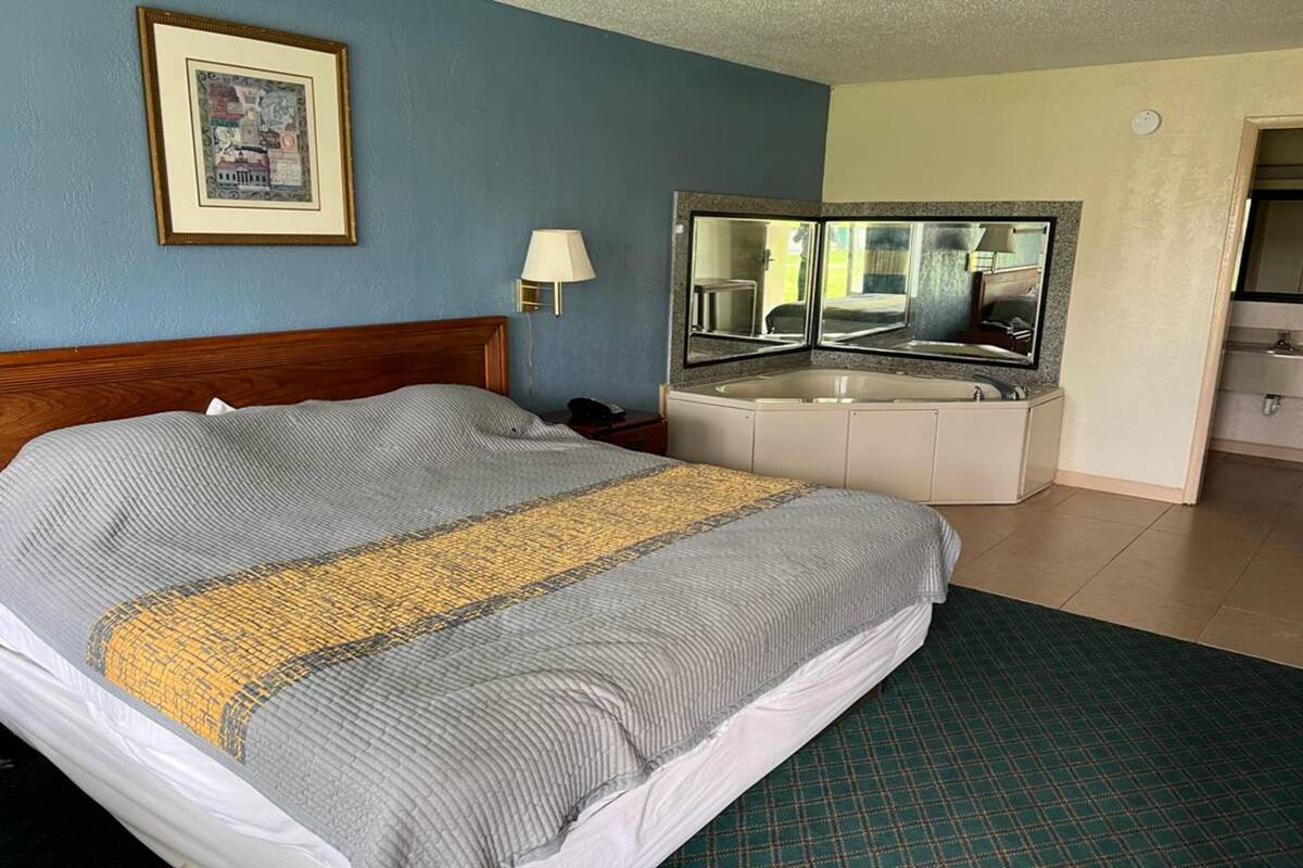 Ein Hotelzimmer mit einem Bett, einem Spiegel, einem Waschbecken und einem gerahmten Bild an der Wand.