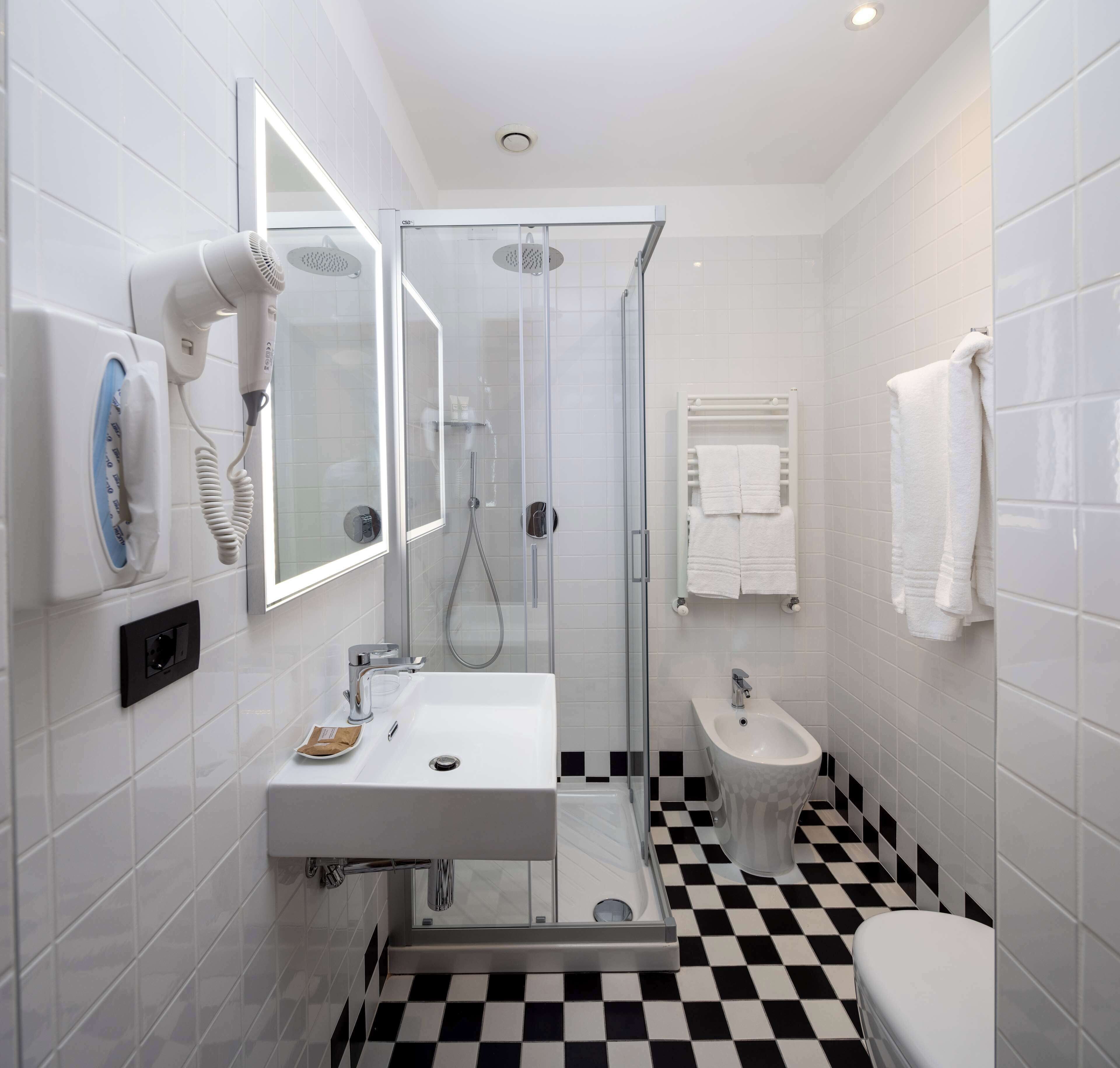 A modern bathroom with a glass-enclosed shower, a white sink, and a bidet.