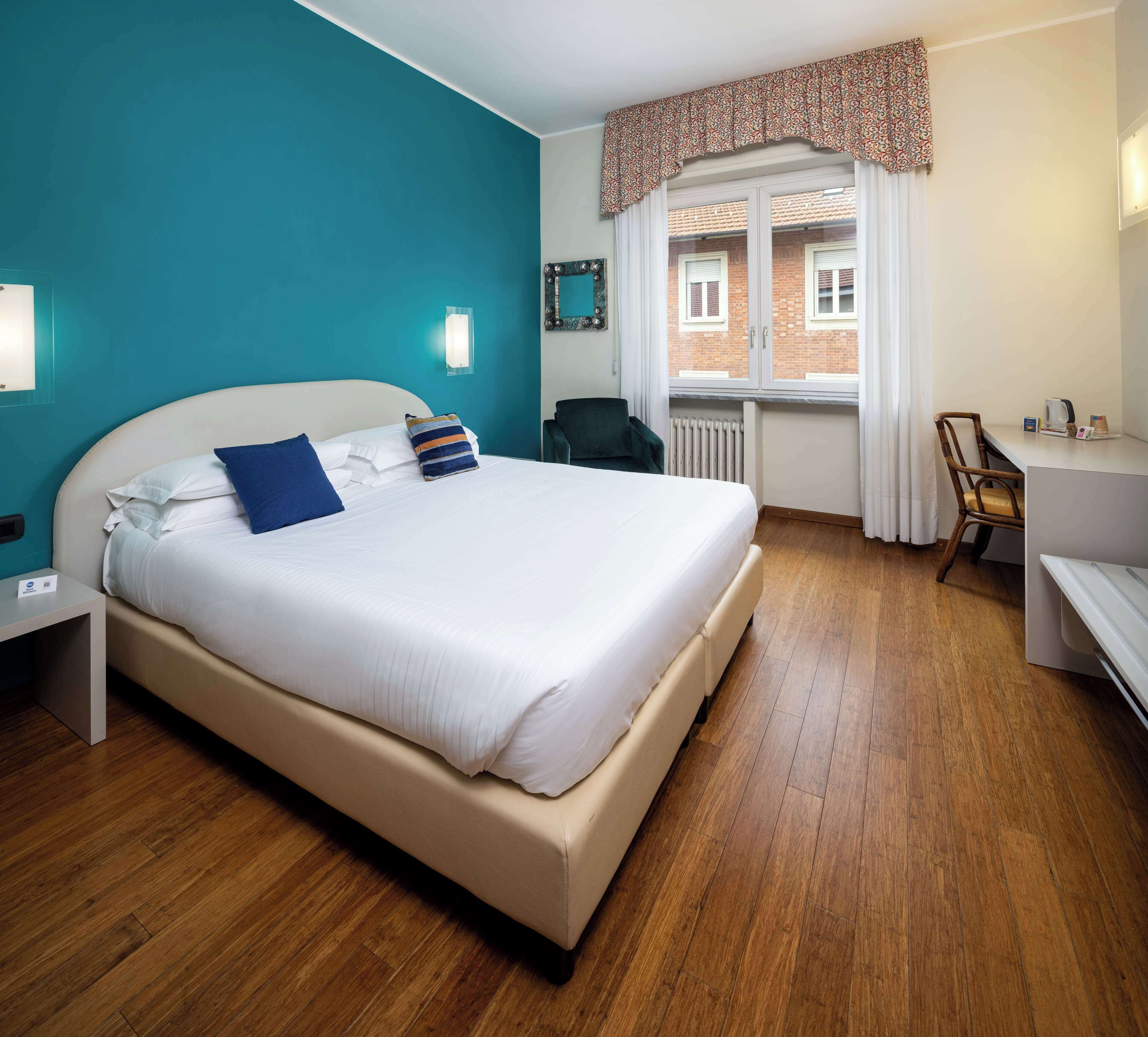 Una camera d'hotel moderna con un letto grande, una scrivania e una finestra con tende.