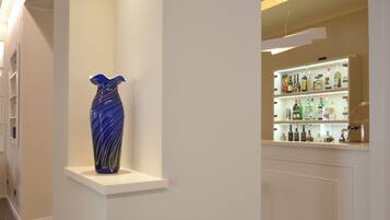Ein Flur mit einer blauen Vase auf einem weißen Regal und einer Bar mit verschiedenen Spirituosenflaschen.