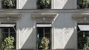 A building with a classic architectural style, featuring a central entrance with a glass door and a decorative metal sign above it. - Le Burgundy Paris (Paris)