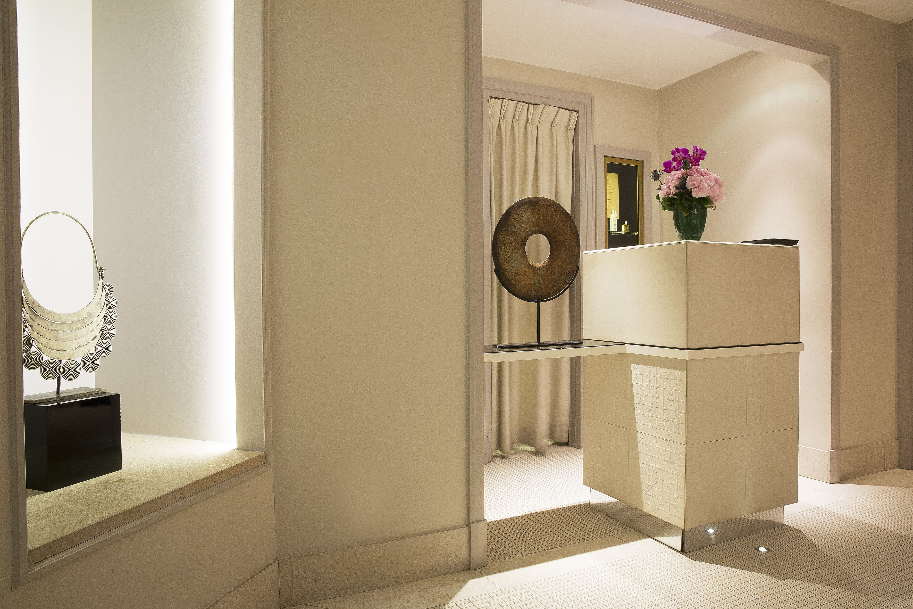 A modern bathroom with a vanity, a mirror, and a vase of flowers.