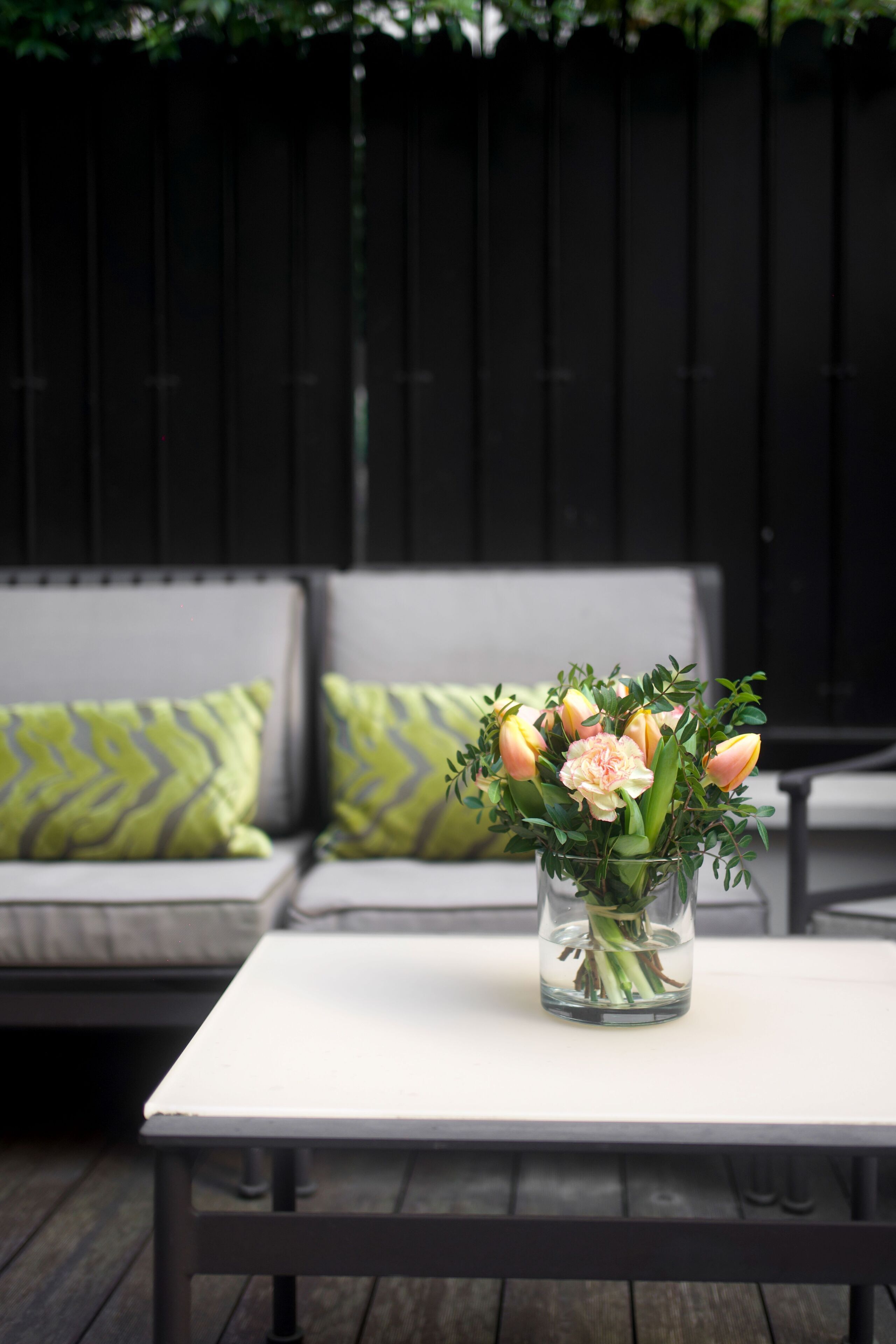 Une table blanche sur laquelle se trouve un vase en verre transparent rempli de fleurs.