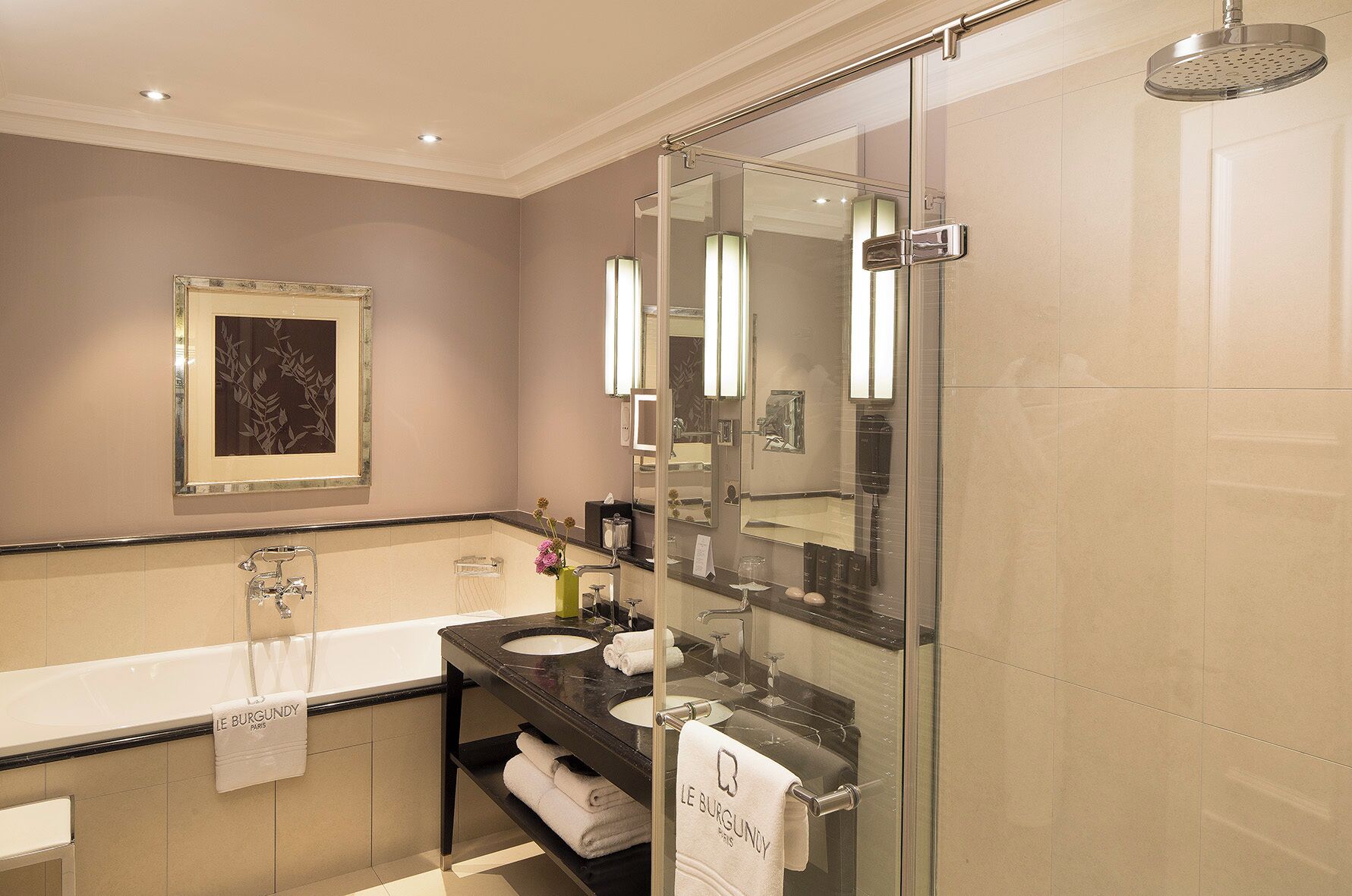 Une salle de bain moderne dotée d’une douche à parois de verre, d’un grand miroir et d’un meuble-lavabo avec un évier et un porte-serviettes.