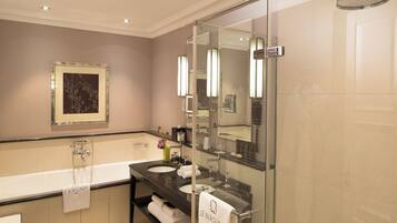 Une salle de bain moderne dotée d’une douche à parois de verre, d’un grand miroir et d’un meuble-lavabo avec un évier et un porte-serviettes.