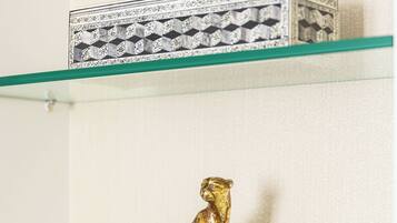 Una figurita de animal dorado sobre una esfera de vidrio transparente, colocada en un estante blanco frente a una pared lisa.
