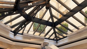 A spacious lobby with a high ceiling, a large abstract sculpture, and modern seating. - Le Burgundy Paris (Paris)